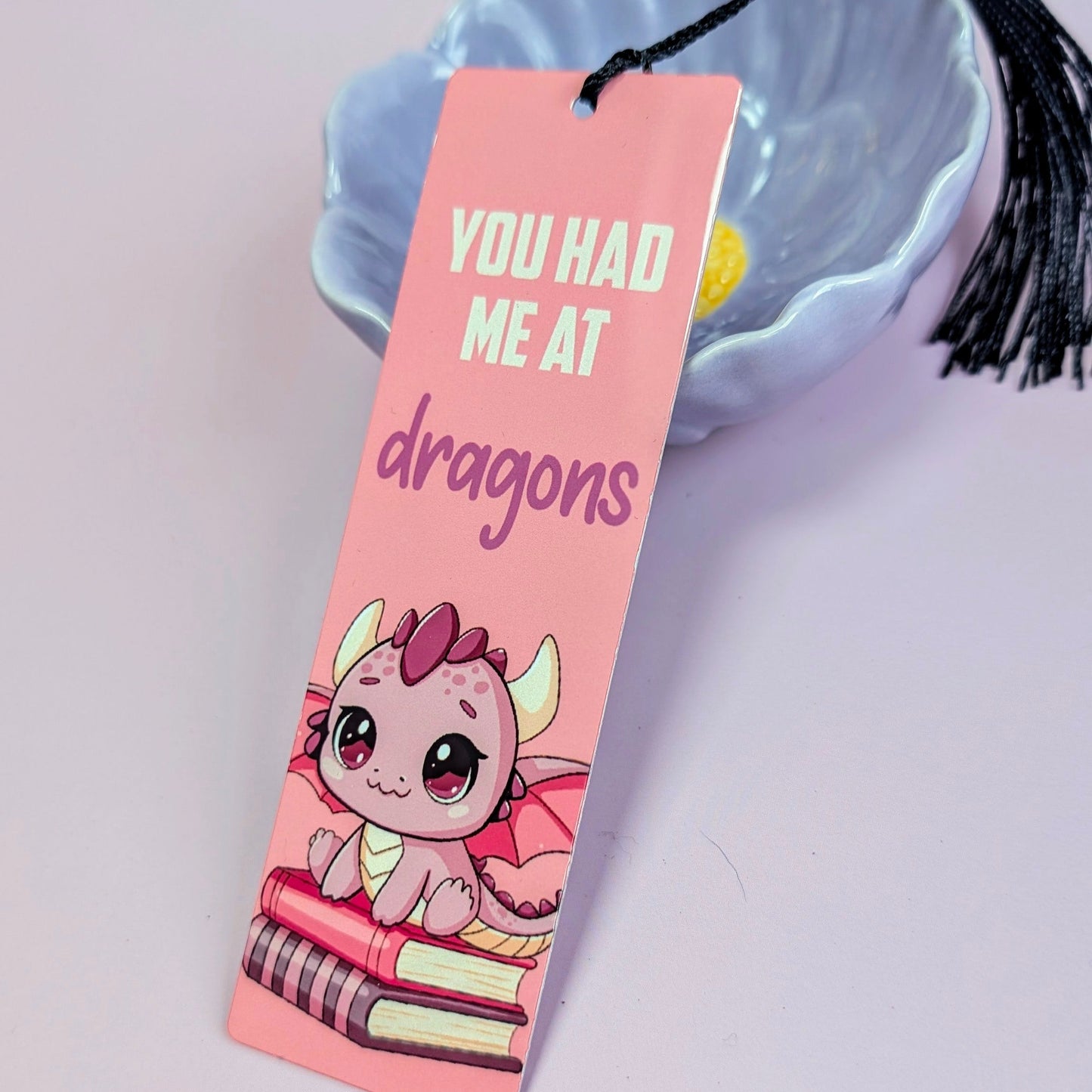 Pink bookmark with a dragon illustration and text 'You had me at dragons' on a light gray background.