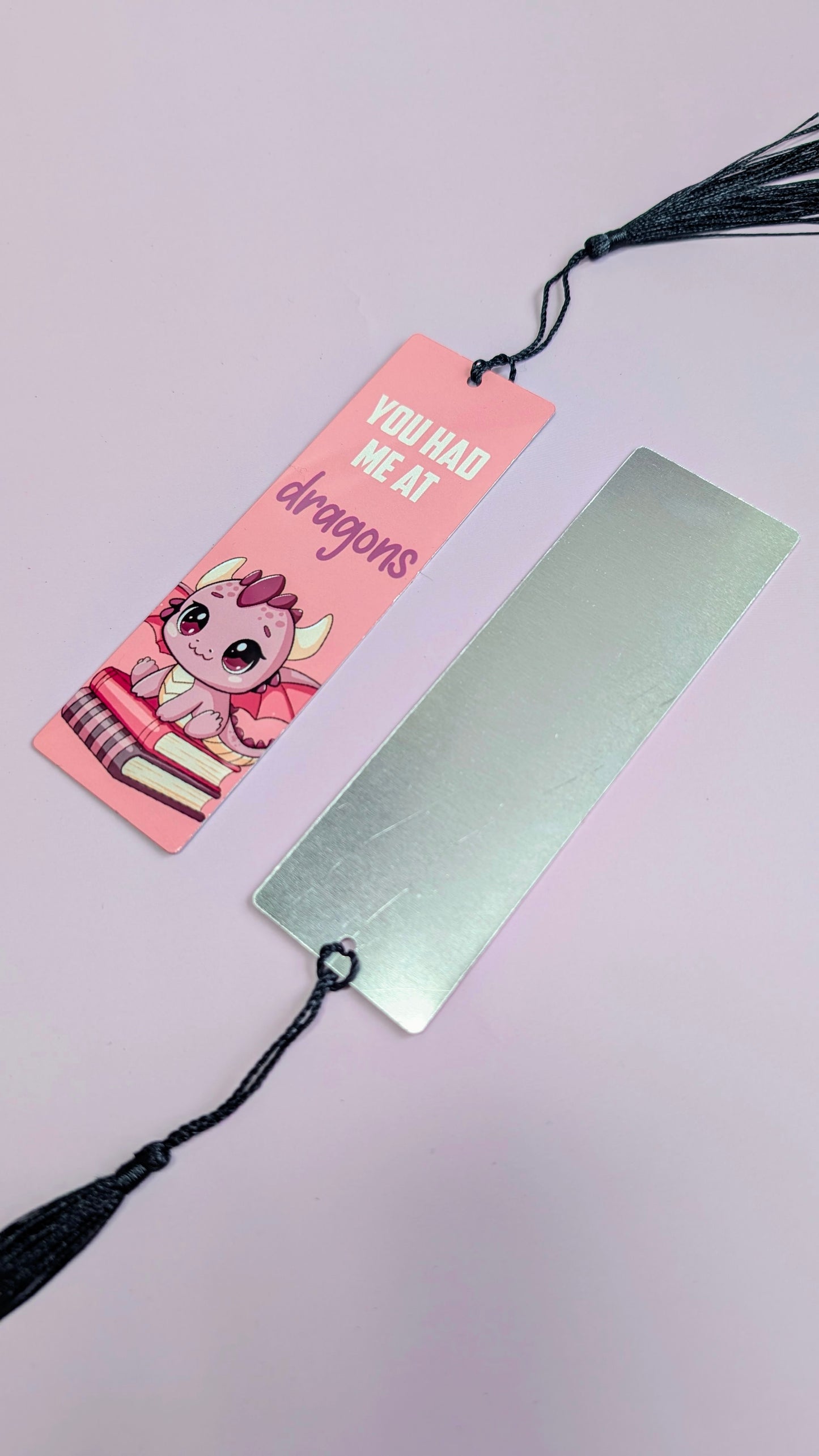 Two bookmarks with tassels on a light pink background