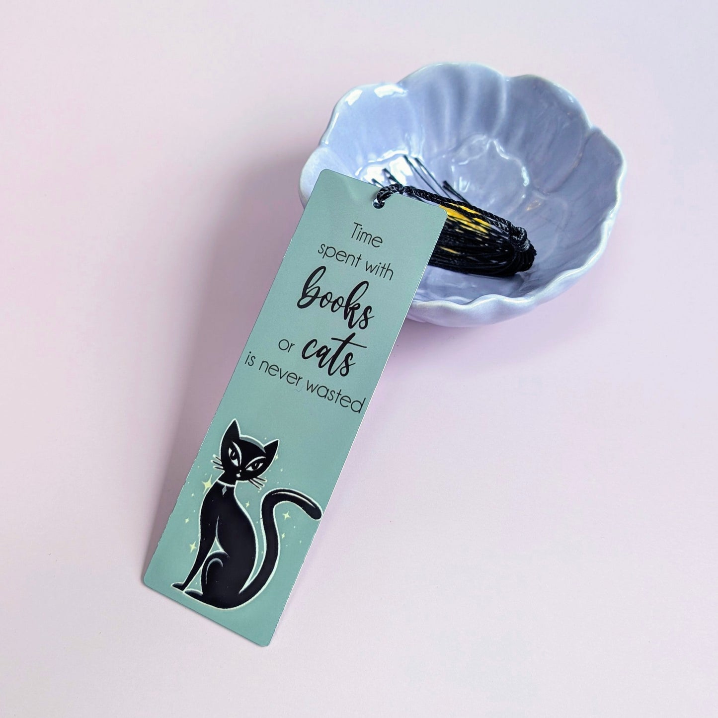 Teal coloured bookmark with black cat design and text 'Time spent with books or cats is never wasted'