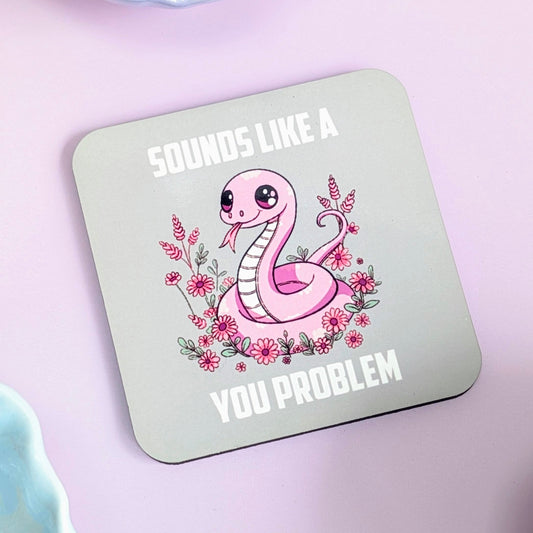 Coaster with a cartoon snake and floral design on a light green background with text "sounds like a you problem"