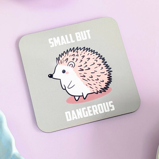 Coaster with hedgehog illustration and text 'Small but Dangerous' on a green background
