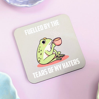 Coaster with a frog illustration and text "fuelled by the tears of my haters" on a green background