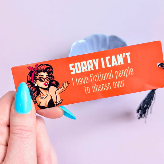 Hand holding a small orange bookmark with a graphic of a woman and text on a light purple background