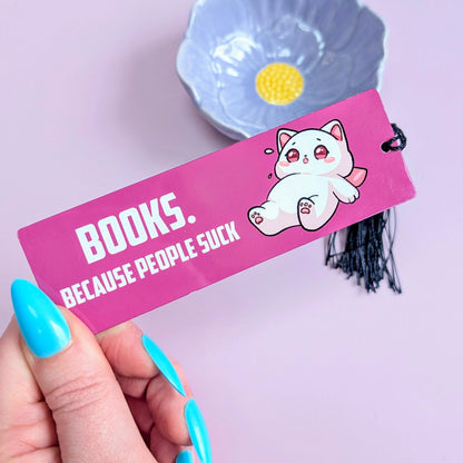 Hand holding a pink bookmark with cartoon character and text against a light purple background